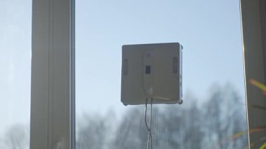 Kare cam temizleme robotu cam yıkıyor. Robotik pencere temizleyicisi mavi gökyüzüne karşı pencere yüzeyinde çalışıyor. Akıllı ev aletleri kavramı