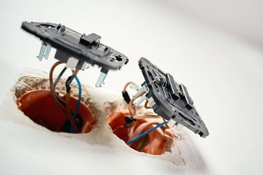 Elektrik şalteri, beyaz duvarın içinde açık kablolar ve montaj kutuları var. Elektrik prizleri yerleştirme işlemi. Elektrik tesisatı, onarım, bakım ve yenileme kavramı