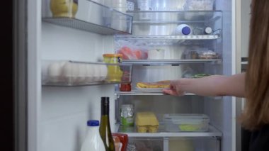 Kadın, ev yapımı turta ya da güveçle birlikte çeşitli gıda ürünleri ve malzemeleriyle birlikte buzdolabından tabak alıyor. Diyet ve sağlıklı beslenme kavramı