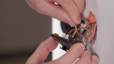Elektrikçi elleri, ev tadilatı sırasında elektrik prizine kablolarla elektrik anahtarı yerleştiriyor. Elektrik işi, bakım, onarım ve ev iyileştirmesi kavramı