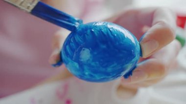 Paskalya kutlaması için yumurta süslemek için mavi boya kullanıyor.