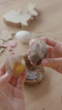 Tüylerle süslenmiş el yapımı Paskalya yumurtalarını tut. DIY tatil dekorasyonu ve bahar sanatı hazırlığı kavramı.
