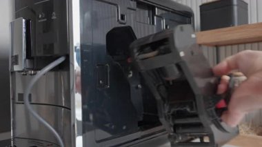 Çağdaş otomatik kahve makinesinden dahili demleme grubu ünitesini çıkaran kişi. Cihaz bakımı, temizlik ve ev kahvesi hazırlama kavramı