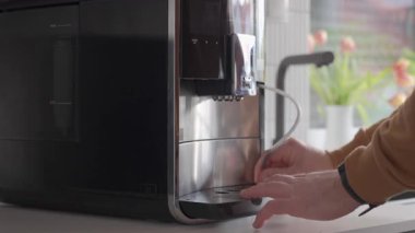 Otomatik kahve makinesinden damlaları ve kahve fincanlarını kaldıran kişi. Mutfak aletlerinin temizlik, bakım ve hijyen anlayışı