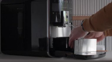 Otomatik kahve makinesinden damlatma tepsisi ve kahve kabı yerleştiren kişi. Mutfak aletlerinin temizlik, bakım ve hijyen anlayışı