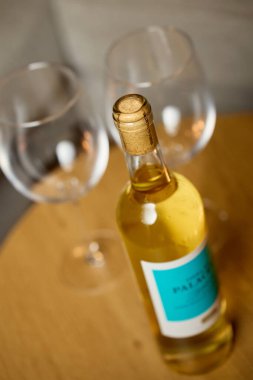 Bir şişe beyaz şarap ve iki boş şarap kadehi ev içi konforlu masada. Romantik yemek kavramı, randevu gecesi ve şarap içmek.