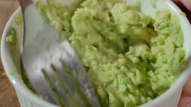 Avokadoyu beyaz kâsede çatalla ezmek. Yaklaş. Ev yapımı guacamole hazırlığı kavramı