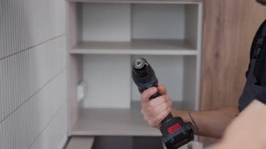 Kurulum sırasında mutfak dolabına bağlı tornavidayla kablosuz matkabı kapat. DIY ev onarımı ve elektrikli araçlar kullanma kavramı