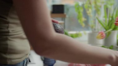 Olgun avokadoları mutfak tezgahına kesme tahtası ve bıçakla koyan bir kadın. Sağlıklı yemek hazırlığı ve taze malzemeler kavramı.