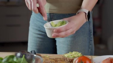 Avokadoyu çatalla beyaz kasede ezen kadın, yaklaş. Ev yapımı guacamole hazırlığı kavramı