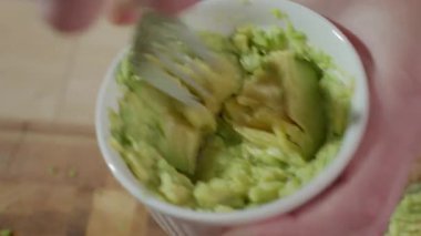 Avokadoyu beyaz kâsede çatalla ezmek. Yaklaş. Ev yapımı guacamole hazırlığı kavramı