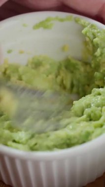 Avokado etini çatalla kaseye sıkıştıran kişiye yaklaş. Sağlıklı kahvaltı, avokado tostu hazırlama ve vejetaryen ev yemeği kavramı.