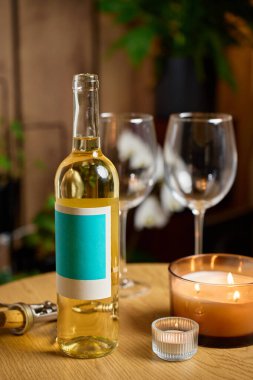 Bir şişe beyaz şarap, iki boş şarap bardağı ve sıcak ev içinde yanan mumlar. Romantik yemek kavramı, randevu gecesi ve şarap içmek.