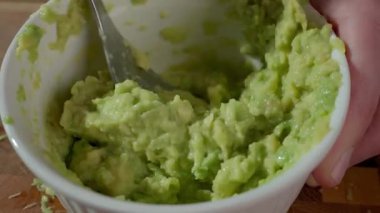 Avokadoyu beyaz kâsede çatalla ezmek. Yaklaş. Ev yapımı guacamole hazırlığı kavramı