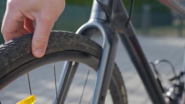 Asfaltlı caddede bisiklet lastiğindeki delik üstüne basınç kontrolü için el sıkışıyor. Bisiklet lastiği patlak. Bisiklet servisi ve bisiklet bakımı kavramı
