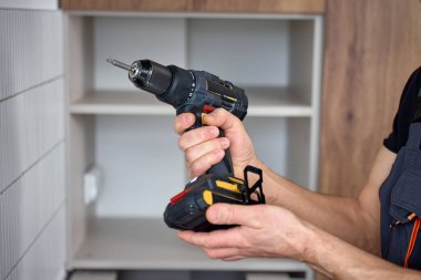 Kurulum sırasında mutfak dolabına bağlı tornavidayla kablosuz matkabı kapat. DIY ev onarımı ve elektrikli araçlar kullanma kavramı