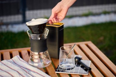 Kağıt filtreyi, cam sürahinin üzerine dökülecek şekilde ahşap açık masa üzerine koyuyor. Elle kahve demleme kavramı