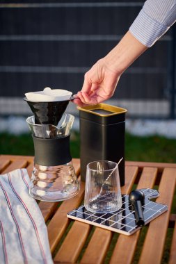 Kağıt filtreyi, cam sürahinin üzerine dökülecek şekilde ahşap açık masa üzerine koyuyor. Elle kahve demleme kavramı