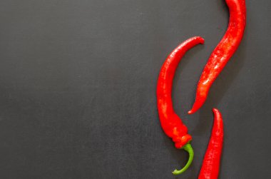 Siyah arka planda kırmızı kırmızı kırmızı kırmızı biber sürüleri. Çiftlik yatağından yeni koparılmış. Yeni acı biber mahsulü.