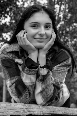 Ekose gömlekli, dağınık saçlı, muzip, neşeli kadının tek renkli portresi. Mutlu yüzlü bir kadın başını ellerinin üzerine koydu..