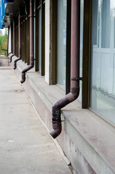 Kahverengi olukları olan bir binanın ön cephesi. Uzak bir perspektifte plastik yağmur boruları. Mimari