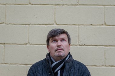 Yüzünde alışılmadık bir ifade olan bir adamın portresi. Orta yaşlı, gri saçlı bir adam sarı bir duvara bakıyor..