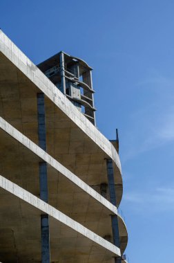 Mavi gökyüzünün arka planında betondan yapılmış geometrik şekil. Modern bir alışveriş merkezinin tamamlanmamış binası. Sanayi geçmişi.