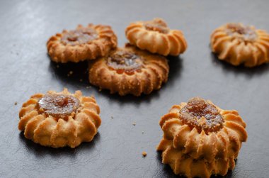 Meyve reçelli kum saati kurabiyeleri. Siyah masada reçelle dolu lezzetli kurabiyeler. Seçici odak