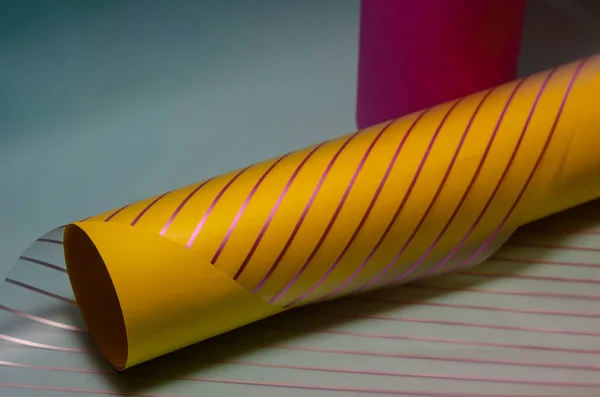 Creative abstract purple and yellow composition on a light blue background. Yellow and magenta cylinder and translucent striped material.