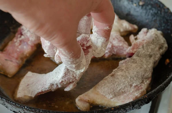 男性の手は熱い鍋に小麦粉でロール生の魚の作品を置きます 鋳鉄フライパンで魚を揚げます 自家製料理の調理 — ストック写真