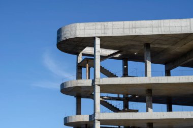 Mavi gökyüzünün arka planında betondan yapılmış geometrik şekil. Modern bir alışveriş merkezinin tamamlanmamış binası. Sanayi geçmişi.