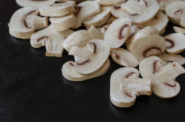 Bir grup ham şampiyon siyah arka planda parçalara ayrıldı. Yemek, malzemeler. Seçici odak