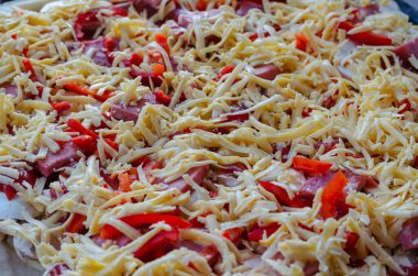 Evde pizza pişirme konsepti. Salam, paprika, tavuk filetosu, mantar, soğan, hamur, kırmızı sos ve rendelenmiş peynir ile pişirme tepsisi. Seçici odak.
