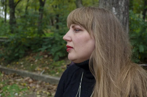 緑の公園の背景に長い緩やかな髪を持つ中年の女性 サイドビュー 最小限の写真編集 — ストック写真