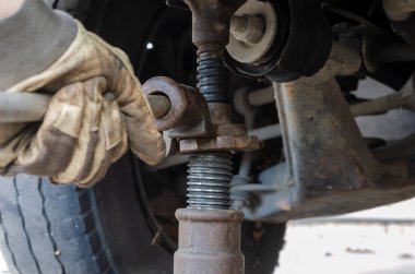 Lastik servisi, araba servisi konsepti. Eldivenle arabayı mekanik kriko ile kaldırıyor. Patlak bir lastiği değiştirmek. Seçici odak.