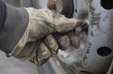Lastik servisi, araba servisi konsepti. Eldivenin içindeki vidaları söküyor direksiyondaki vidayı söküyor. Patlak bir lastiği değiştirmek. Yan görüş. Seçici odak.