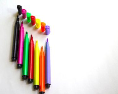Beyaz arka planda rengarenk keçeli kalemler. Yedi parlak renkli keçeli kalem. Yaratıcılık, çizim, ev eğlencesi konsepti. Seçici Odaklanma.