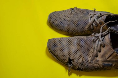 Sarı arka planda yırtık sarı yaz ayakkabıları. Bir çift ağır giysili deri ayakkabı..