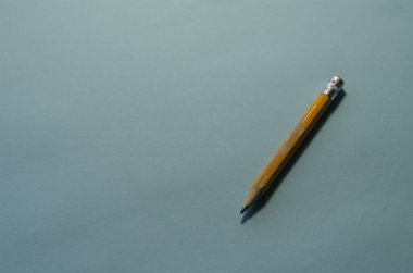 Minimalist temalı arka plan ve açık mavi yüzeyde eski sarı tahta bir kalem. Mühendislik, muhasebe, iş, eğitim kavramı.