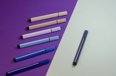 İki tonluk arka planda pastel renkli keçeli kalemler. Çizim için yedi işaret. Yakın çekim, seçici odaklanma.