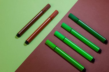 Yeşil ve kahverengi keçeli kalemli yaratıcı iki renkli kompozisyon. Dört yeşil kaleme karşı iki kahverengi keçeli kalem..