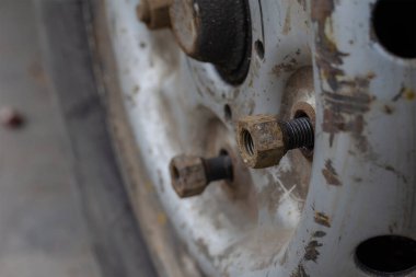 Lastik servisi, araba servisi konsepti. Direksiyondaki vidalanmamış paslı cıvatalara yakın çekim. Patlak bir lastiği değiştirmek. Yan görüş. Seçici odak.