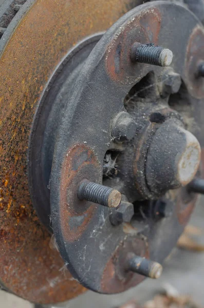 Close-up of the wheel hub without the wheel. Front wheel hub with studs and rusted brake disc. Auto shop. No people.