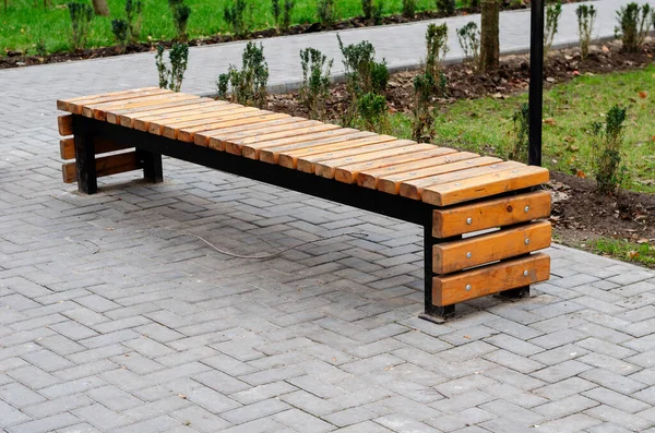 Yaratıcı boş ahşap park bankı. Metal ve ahşap parmaklıklardan yapılmış U şeklinde bir bank. Modern şehir yaşam tarzı