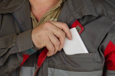 Cebine beyaz bir akıllı telefon koyan bir adamın yakın çekimi. İş için özel kıyafetler giyen bir adam. Kırmızılı özel gri üniforma. Ön manzara. Seçici odak.