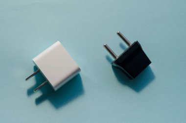 Siyah ve beyaz değiştirilebilir DC ve AC prizleri. Mavi arka planda ABD ve Avrupa için duvar adaptörleri.
