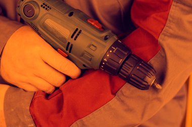 İş için gri kırmızı elbiseli bir adam elinde bir tornavida tutuyor. Yakın plan, seçici odaklanma. Renkli fotoğraf