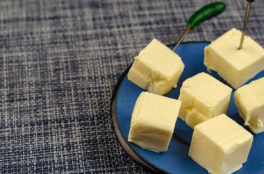 İşlenmiş peynir, mavi bir tabakta doğranmış. Biftekli porsiyon peynirin yakın çekimi. Yiyecek, malzeme.