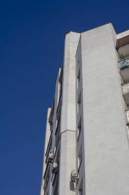 Mavi gökyüzüne karşı apartmanın zemin manzarası. Güneşli bir günde beyaz bina. Emlak, kiralama..