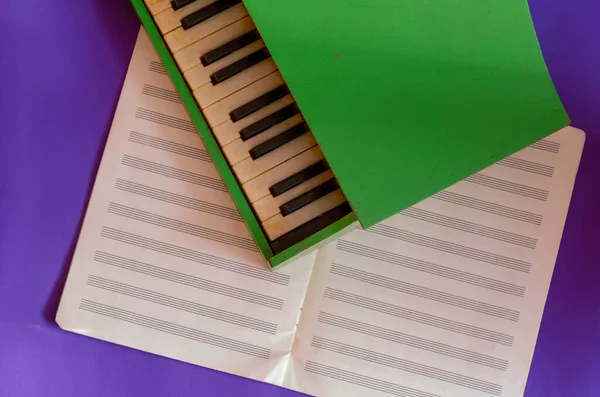 Piano Verde Encuentra Encima Cuaderno Música Abierta Sobre Fondo Azul — Foto de Stock